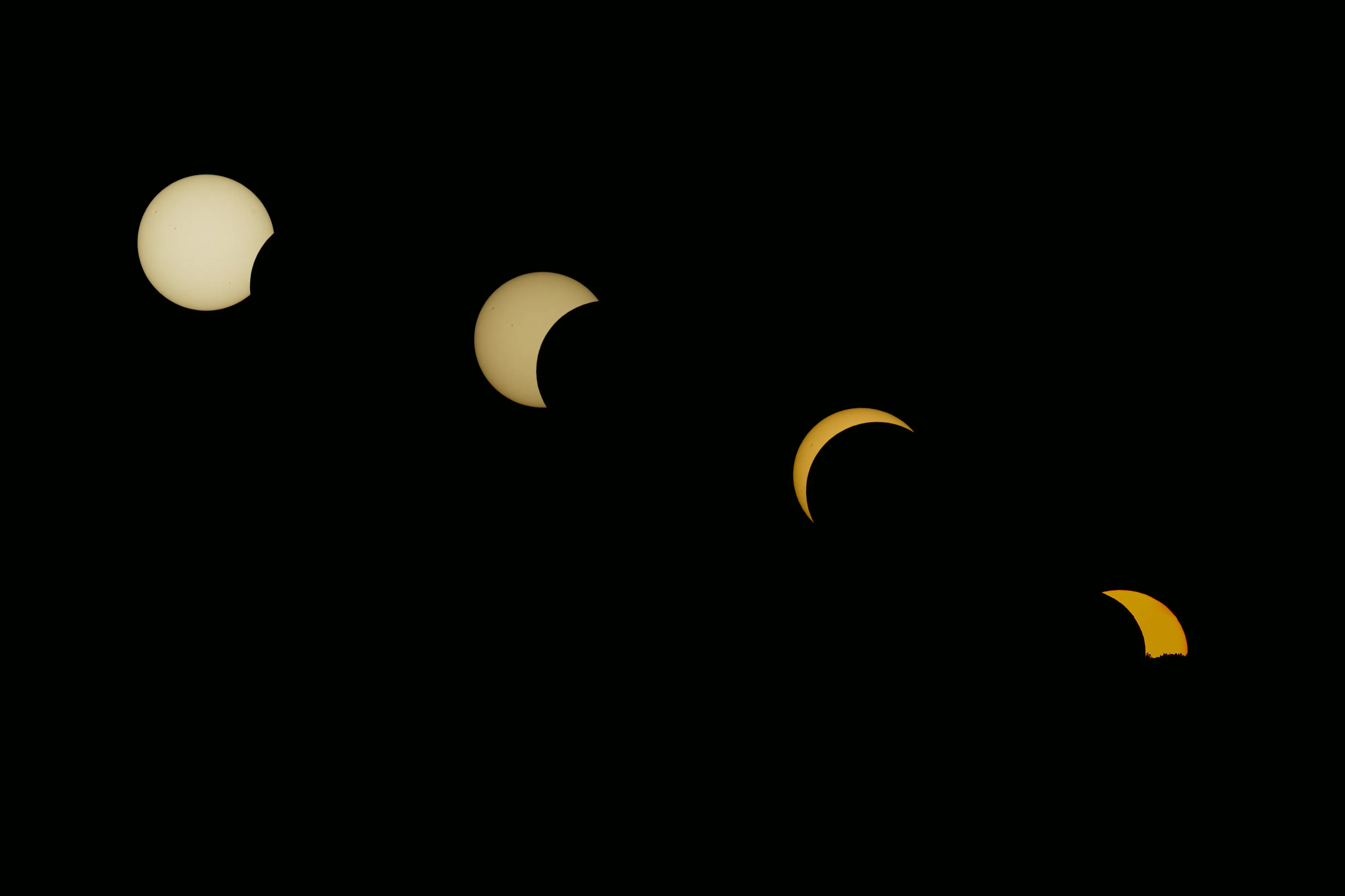 Four phases of a solar eclipse composed against a black background
