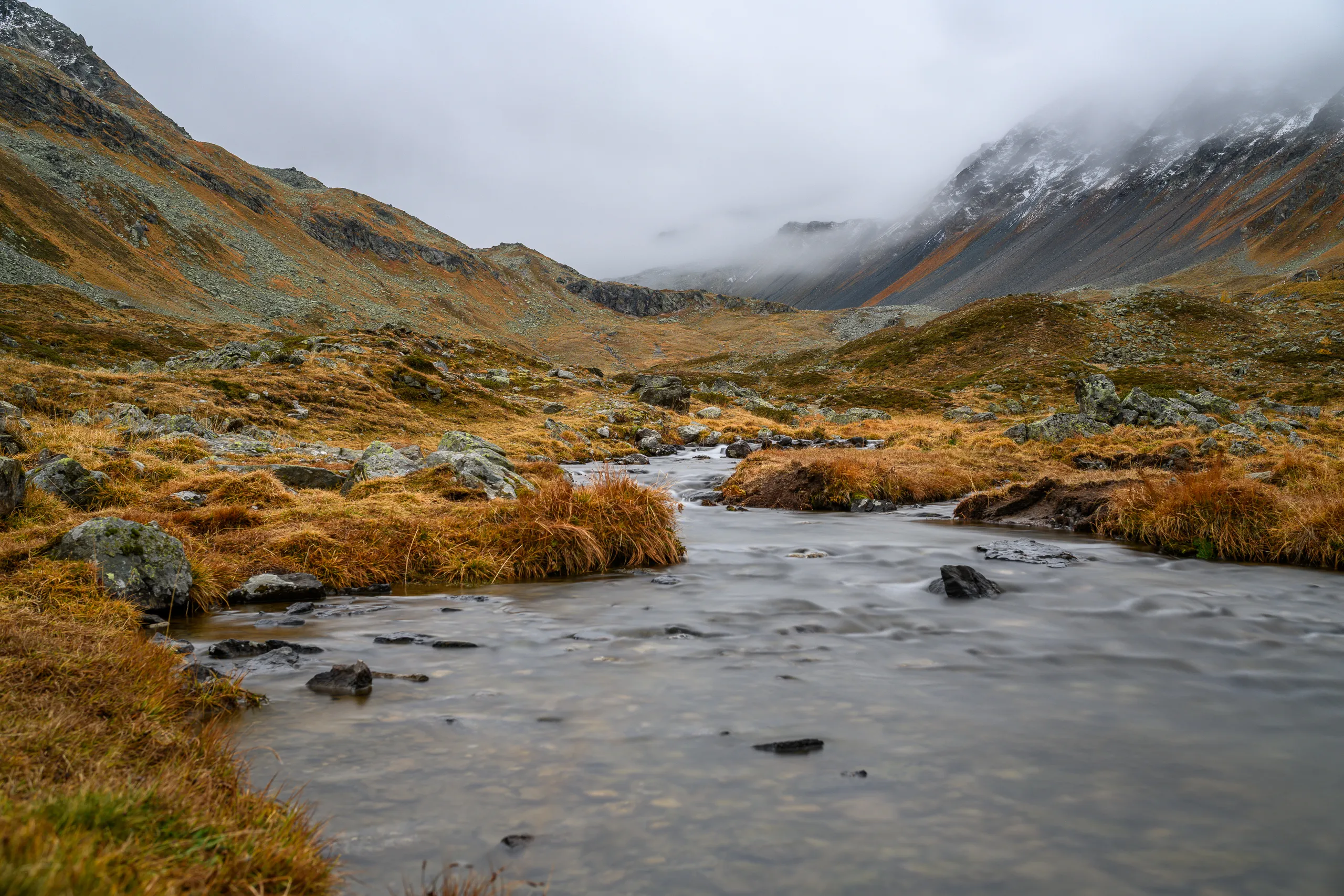 Shallow river crossing an alpine landscape in autumn colours