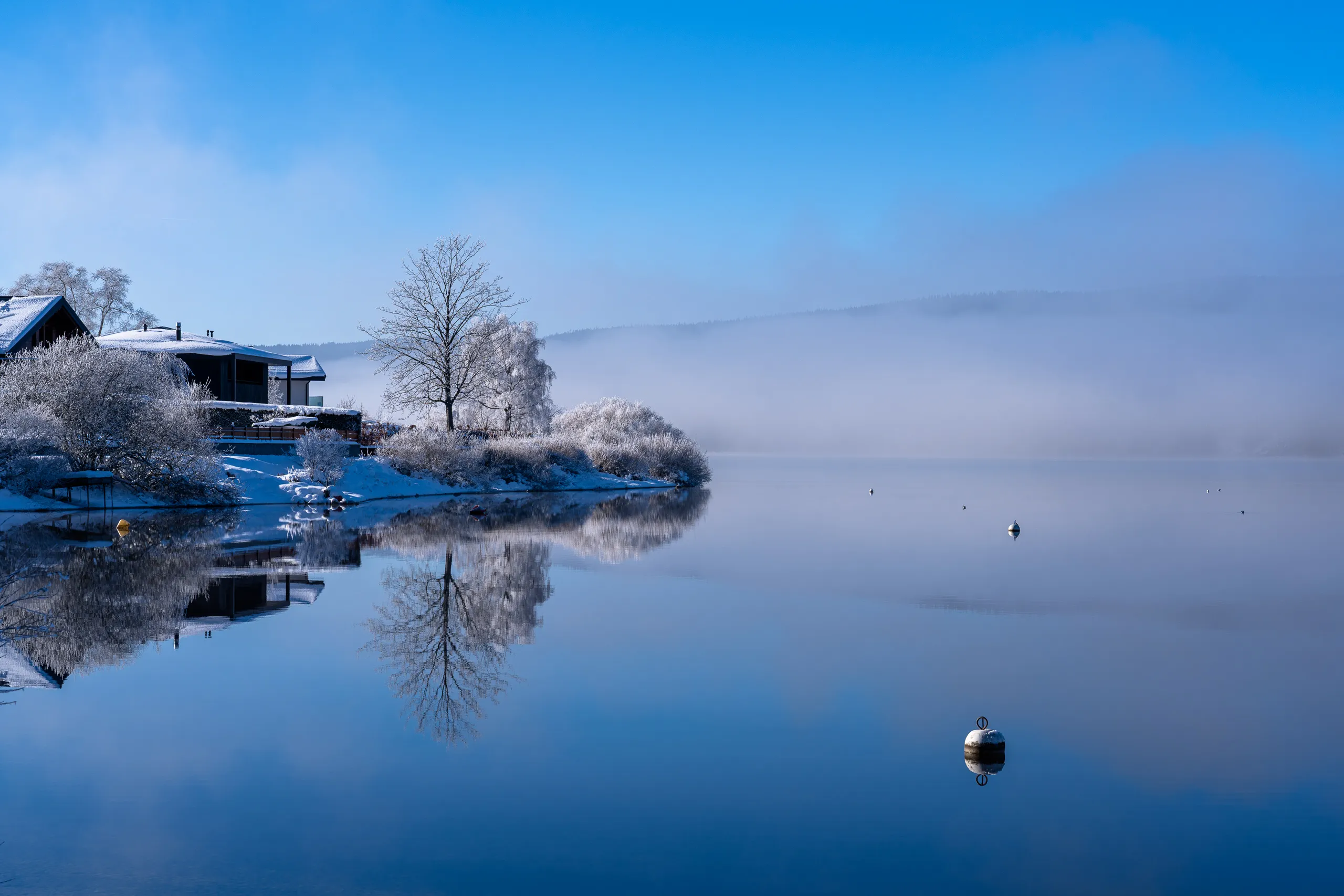 Calm lake reflecting the sky and shoreline in soft light